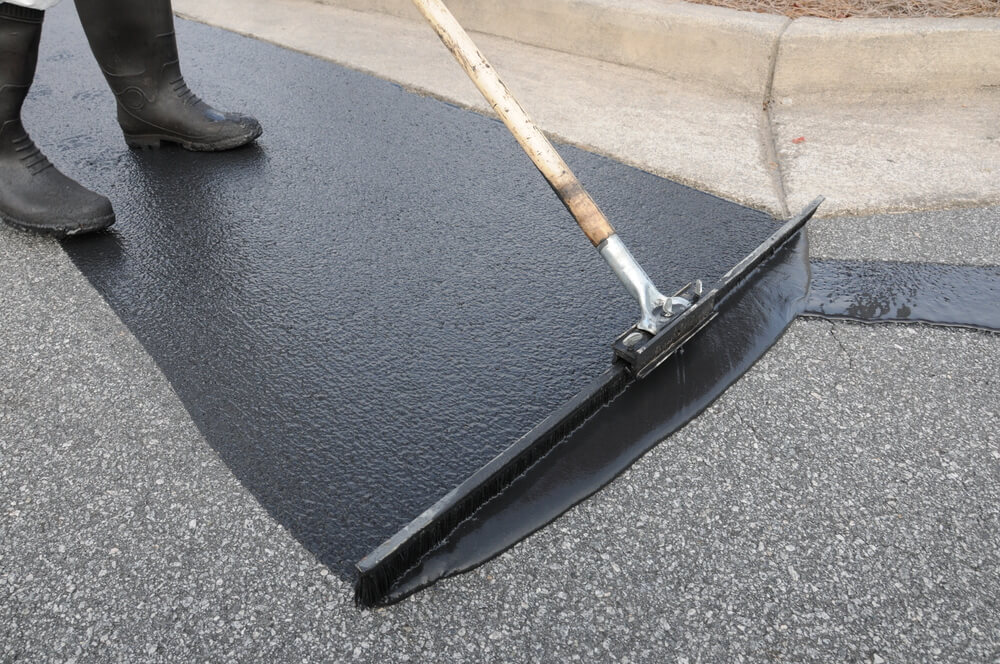 Close up of driveway sealant being applied with a squeegee brush